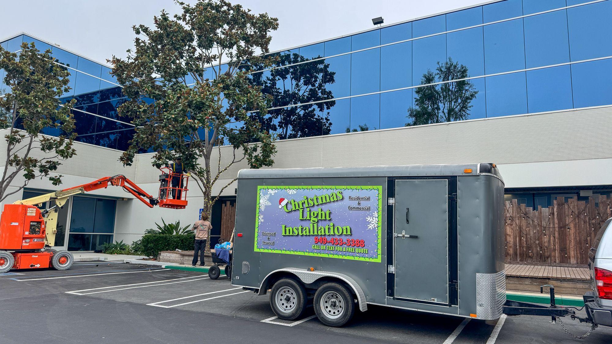 Work trailer and an orange boom lift parked at an office building during an installation